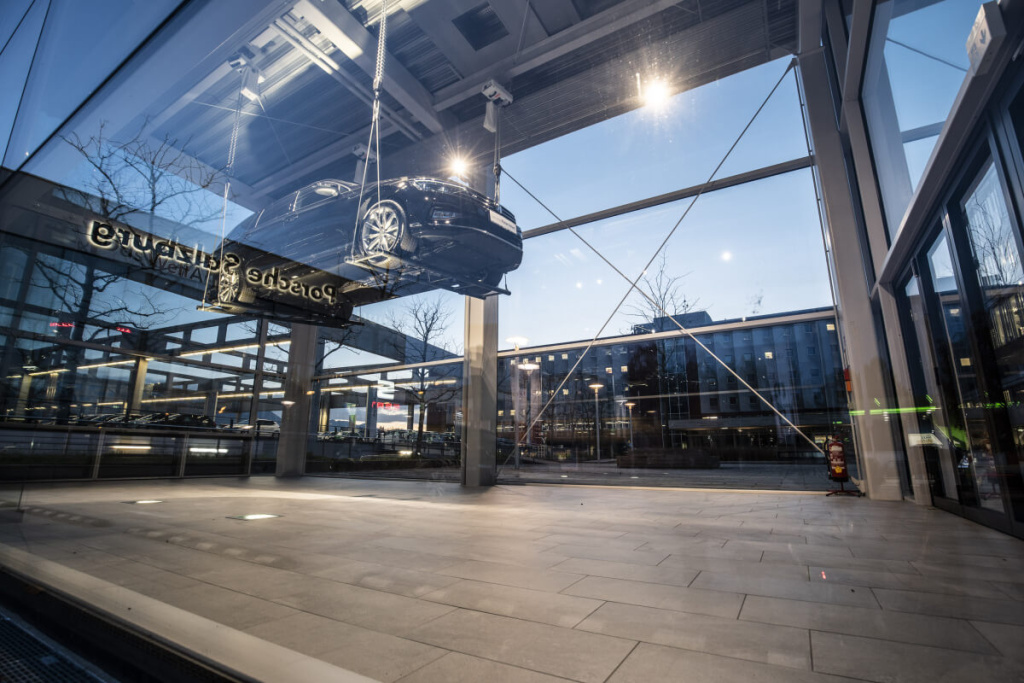 Porsche-Fahrzeug schwebt in moderner Verkaufsfläche in Salzburg bei Abenddämmerung.
