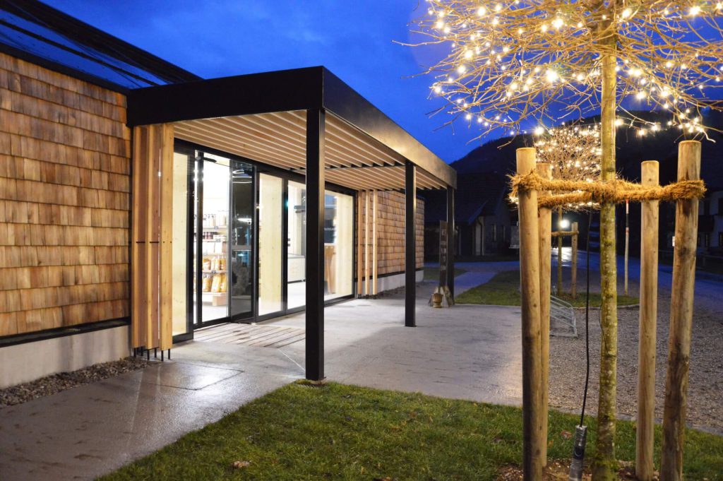 Moderne Architektur des Selbstbedienungs-Hofladens bei Nacht mit dekorativer Beleuchtung.